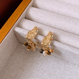 Detailed close-up of vintage gold earrings with hanging tiger eye stones and pearls