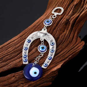 Tribal evil eye horseshoe metal pendant with blue glass charms on dark wood surface