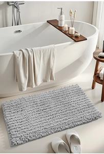 Detail of grey chenille bath mat showing absorbent texture near a white bathtub