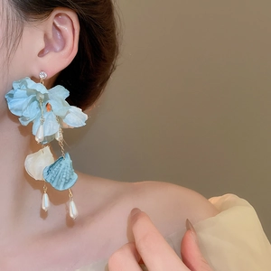 Detail of light blue fabric flower earrings with pearls and long tassel fringe