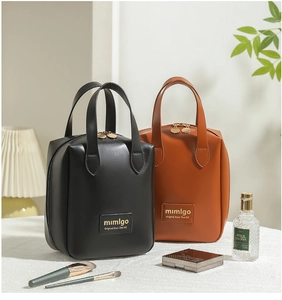 Detail of PU leather shell makeup bags in black and caramel with gold dual zippers