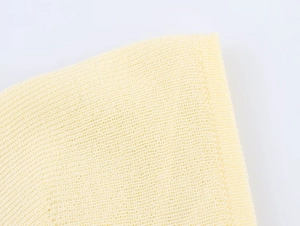 Macro shot of light yellow knit fabric showing detailed texture and high-quality stitching