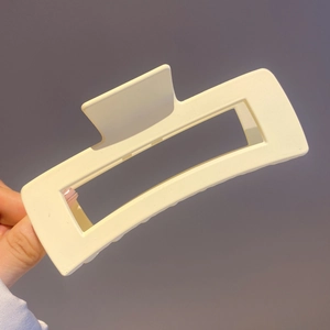 Detail showing hand-held matte beige rectangular hair claw clip for updo hairstyles