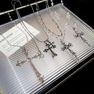 Collana con ciondolo a croce gotica con strass e perle su sfondo strutturato