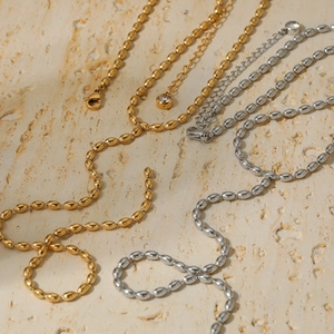 Minimalistische Y-förmige Bohnenkette in Gold und Silber auf Stein-Hintergrund