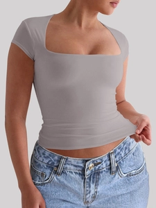 Gros plan d'un t-shirt sport gris à col carré montrant l'élasticité du tissu souple