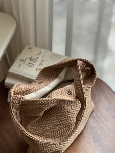 Close-up of beige woven texture canvas bag featuring a metal magnetic buckle closure
