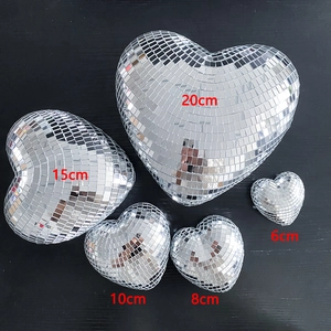 Silver mirror heart-shaped disco balls in five different sizes on black wood background