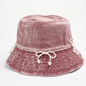 Close-up of pink denim bucket hat with elegant pearl bow details and washed texture