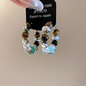 Detail of ethnic style hoop earrings with tiger eye beads and silver metal accents