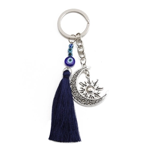 Detail of cross and evil eye keychain with crescent moon pendant and blue silk tassel