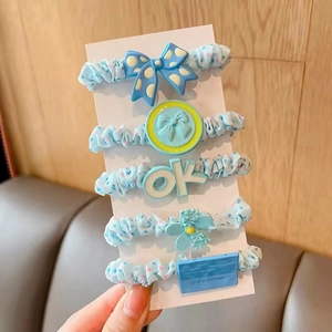 Detailed view of five blue polka dot hair ties with decorative bows and floral charms