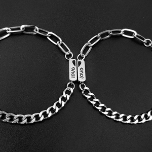 Detail of couple bracelets with interlocking heart pendants and engraved love letters