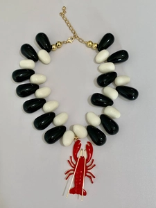 Close-up of ocean-style necklace with white water-drop beads and a red lobster pendant