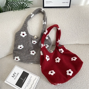 Detail of knitted floral tote bags in grey and burgundy on a modern white sofa