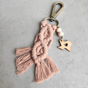 Macro detail of hand-woven cotton keychain with wooden Texas charm and heart cutout