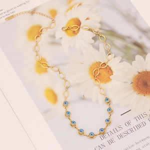 Collier en acier doré avec pendentifs mauvais œil bleus sur une carte à motifs marguerites