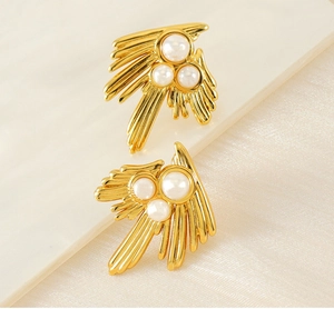 Macro shot of 18K gold irregular swallow feather earrings with white pearl details