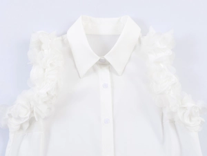Detail of white sleeveless shirt with floral shoulder accents and classic lapel collar