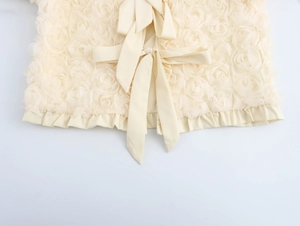 Detail of 3D rose textures and a large back bow tie on this beige French cardigan