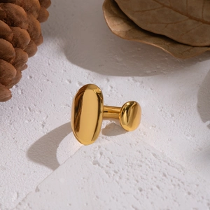 Polished gold geometric double oval open ring displayed on a natural stone base