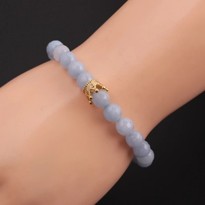 Detail of 8mm light blue beaded bracelet with gold crown charm on model wrist