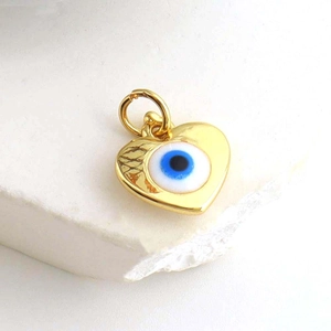Macro view of gold plated heart evil eye charm with blue zircon inlay for jewelry DIY