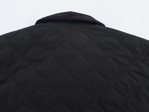 Close-up of black quilted jacket featuring a corduroy collar and diamond stitch patterns