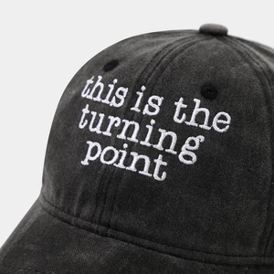 Detail of white embroidery 'this is the turning point' on washed cotton baseball cap