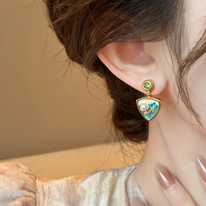 Close-up of vintage flower earrings with green gemstone and white pearl on model