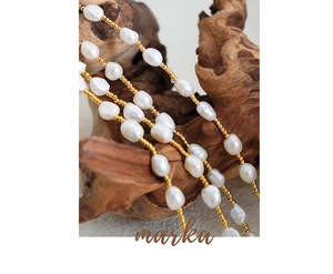 Detail of freshwater baroque pearls and gold beads draped over textured wood surface