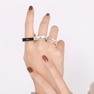 Close-up of three gold stacked rings with black, white and pink rectangular gemstones