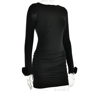 Détail de la robe courte noire avec tissu plissé et fleurs 3D sur les poignets