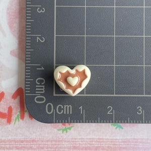 Miniature resin heart charms in white and brown shown next to a ruler for size reference