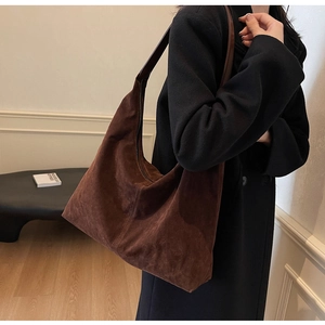 Side view of large brown suede tote bag worn on shoulder showing capacity and drape