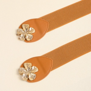 Detail of brown elastic belts with golden flower metal buckles on beige background