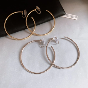 Detailed view of large gold and silver hoop ear clips with resin comfort pads on black leather