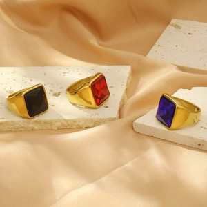 Detailed shot of gold plated rings with vibrant square gemstones on stone and silk