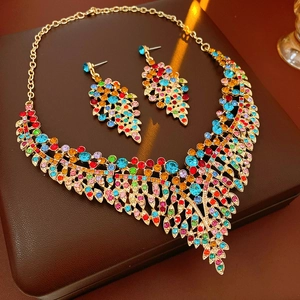 Macro view of vintage leaf earrings and necklace set with colorful crystals and gold finish