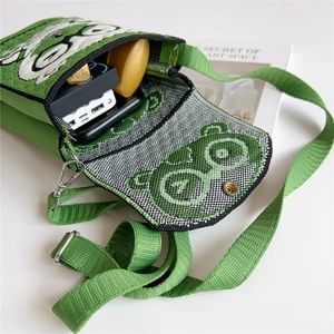 Close-up of green knitted mini crossbody bag showing interior storage and cartoon bear detail
