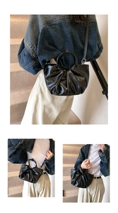Detail view of black pleated cloud bag with metallic ring handle and long shoulder strap