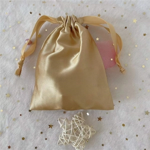 Detail of a golden satin drawstring gift bag with smooth silk texture for cosmetics