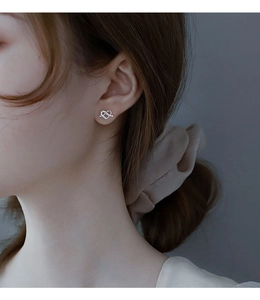 Macro view of sterling silver heart earrings with white cubic zirconia on a model ear