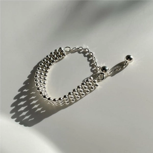 Detail of adjustable 925 silver beaded bracelet with sliding clasp on white surface