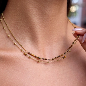 Double-layered gold necklace with tiger eye stone beads and gold accents on a model