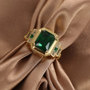 Vintage style gold-plated ring with emerald-cut green zircon on brown silk background