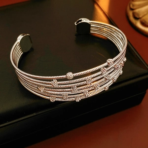 Détail d'un bracelet ouvert argenté multicouche sur un fond de boîte à bijoux en cuir noir