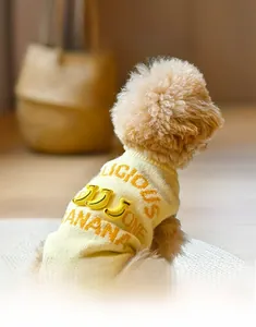 Detail of knitted dog sweater featuring 3D banana decorations and woven text on back