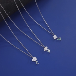 Details von Silberhalsketten mit weißen und rosa Emailleblumen und grünen Blättern