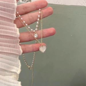 Detail of double-layer necklace with white pearls and a heart-shaped cat-eye stone pendant